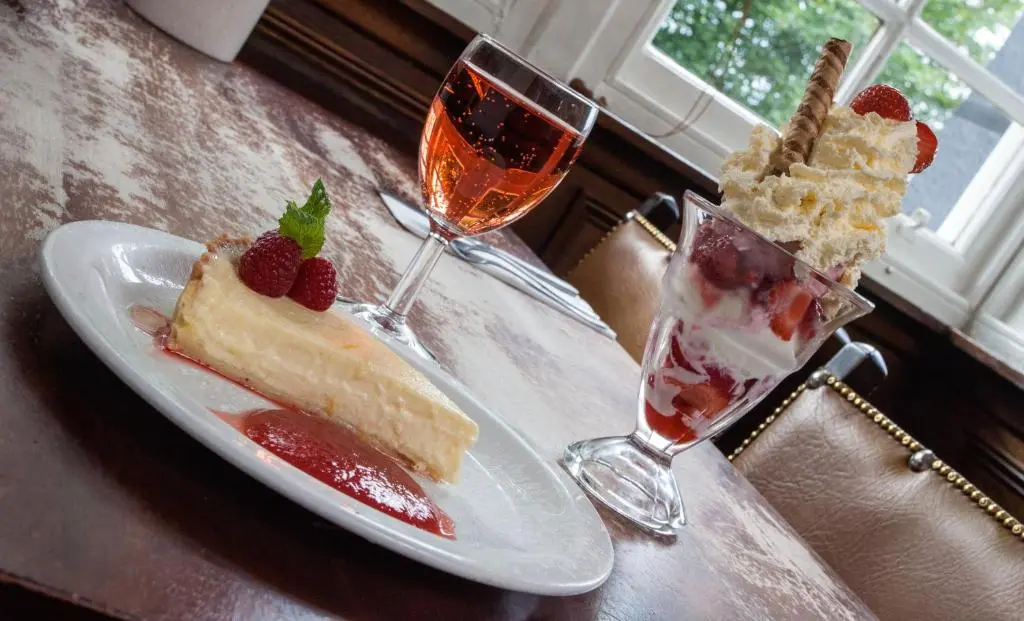 a table with two slices of cake and two glasses of wine at The Shandwick Inn in Tain
