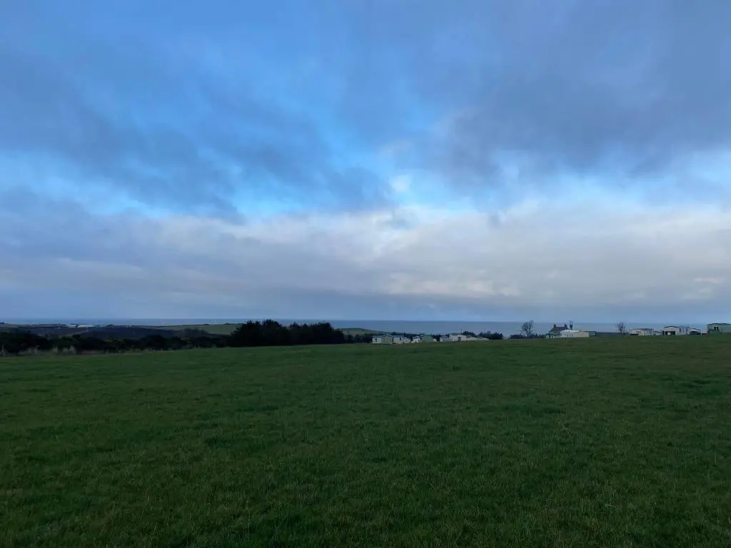 a field of green grass with a cloudy sky at No 56 Headiton Caravan Park in Banff