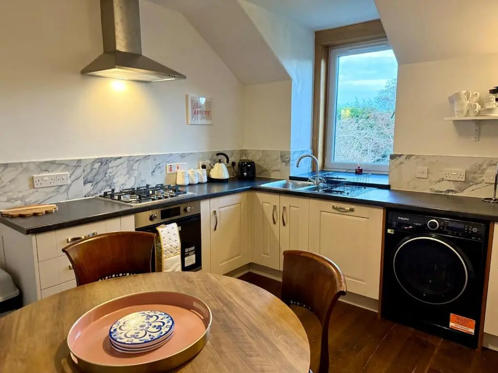 a kitchen with a table and a stove and a window at The Yellow Door in Inverness
