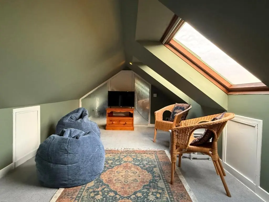 a attic room with a bed and chairs and a window at The Yellow Door in Inverness