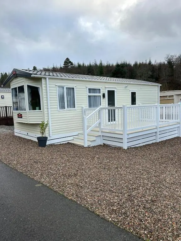 a white house with a porch on a gravel yard at Annas Escape Burnside Moray in Fochabers