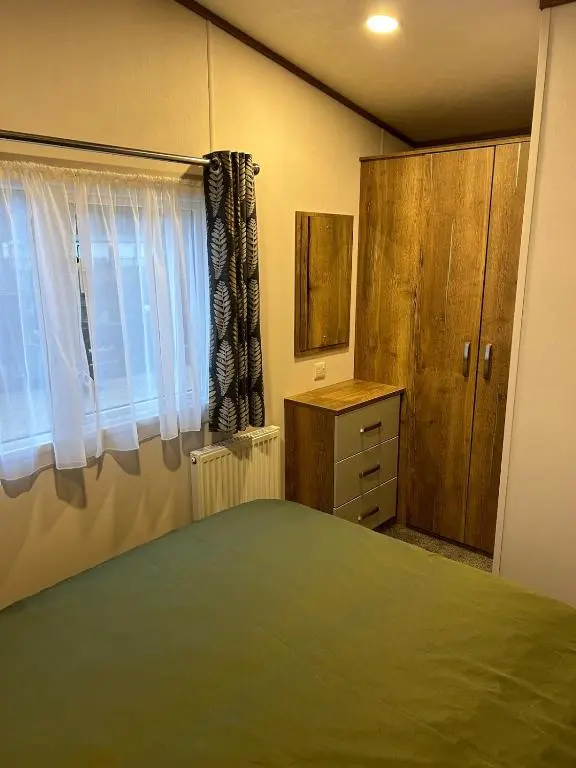 a bedroom with a bed and a dresser and a window at Annas Escape Burnside Moray in Fochabers