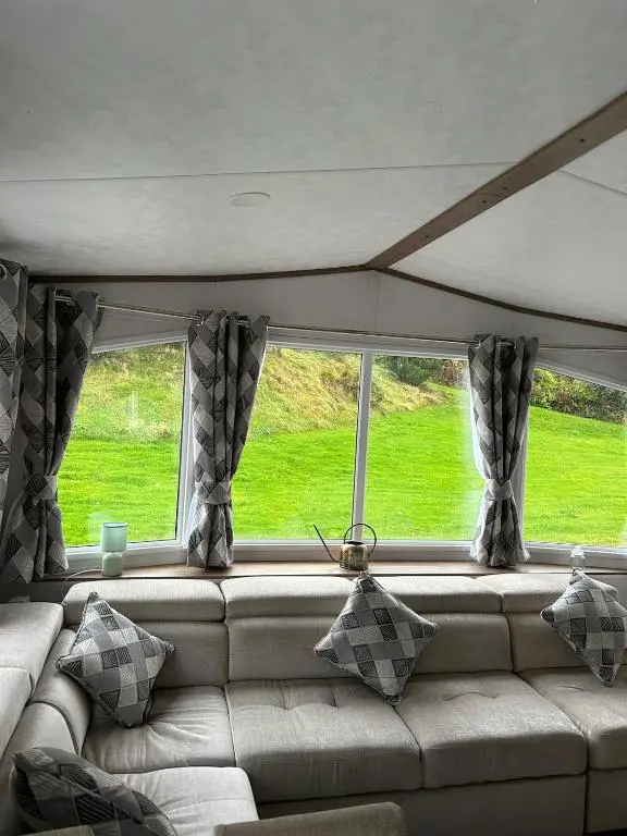 a living room with a couch and two windows at Annas Escape Burnside Moray in Fochabers