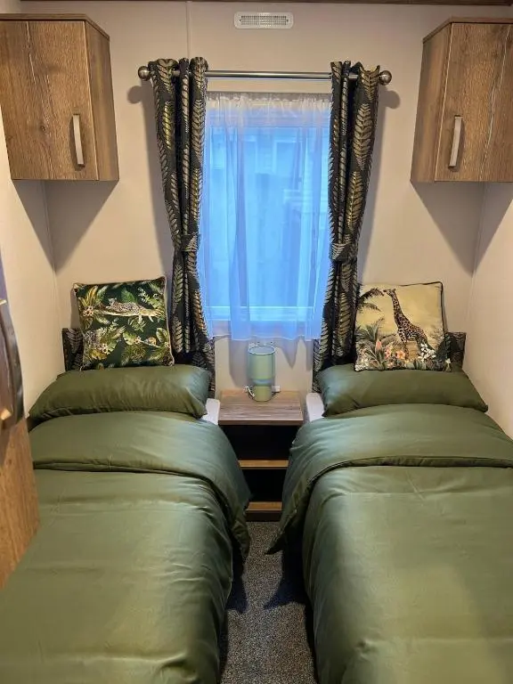 two beds in a room with a window at Annas Escape Burnside Moray in Fochabers