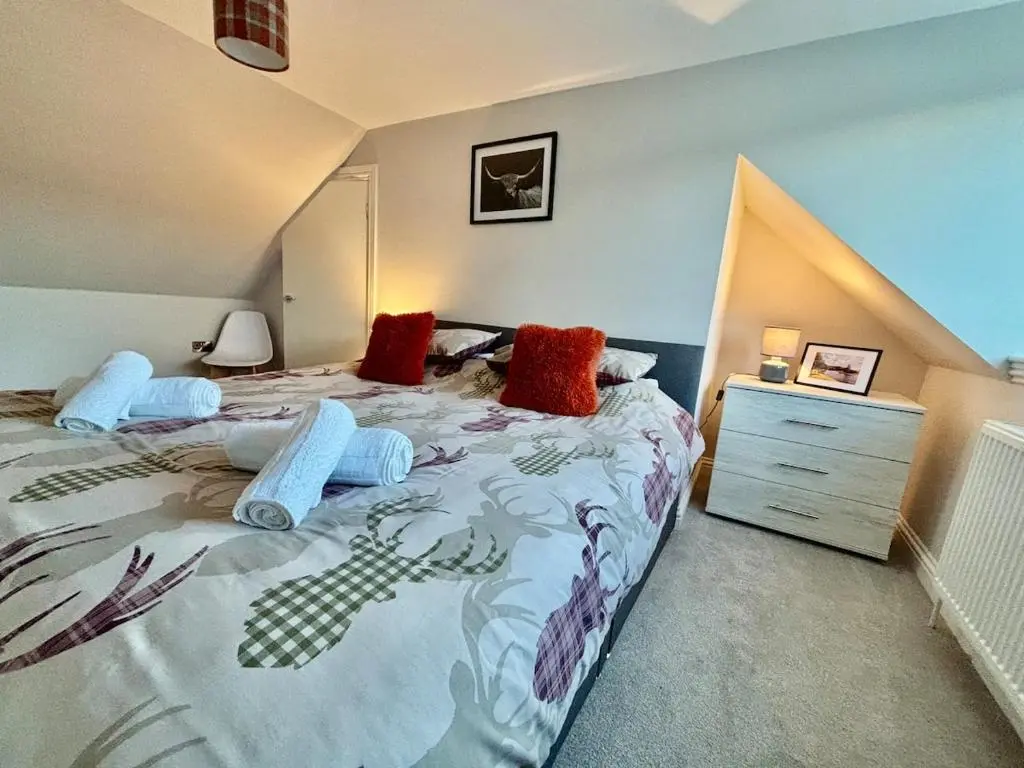a bedroom with a large bed and a dresser at Cosy cottage in idyllic Speyside setting in Rothes