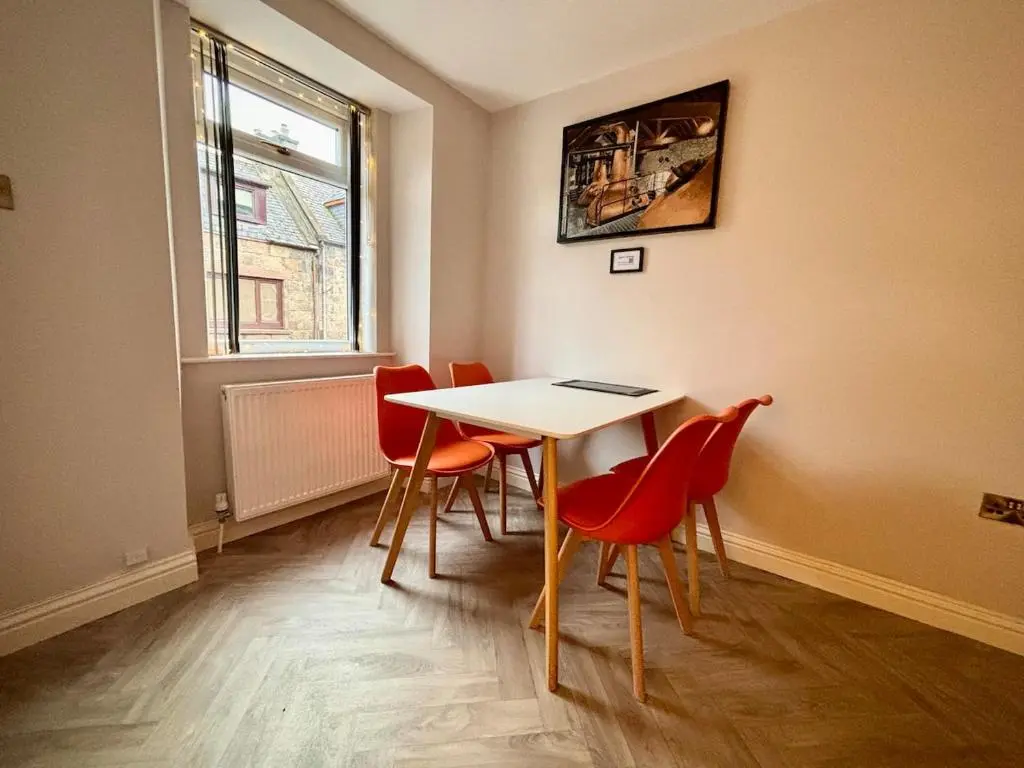 a dining room with a table and red chairs at Stunning Speyside retreat, ideal for Whisky lovers in Rothes