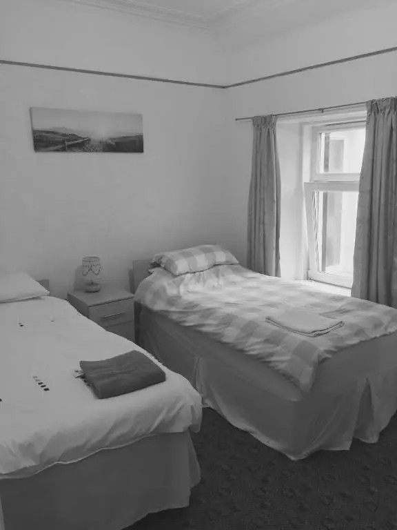 two beds in a room with a window at Grant Arms Hotel in Cullen