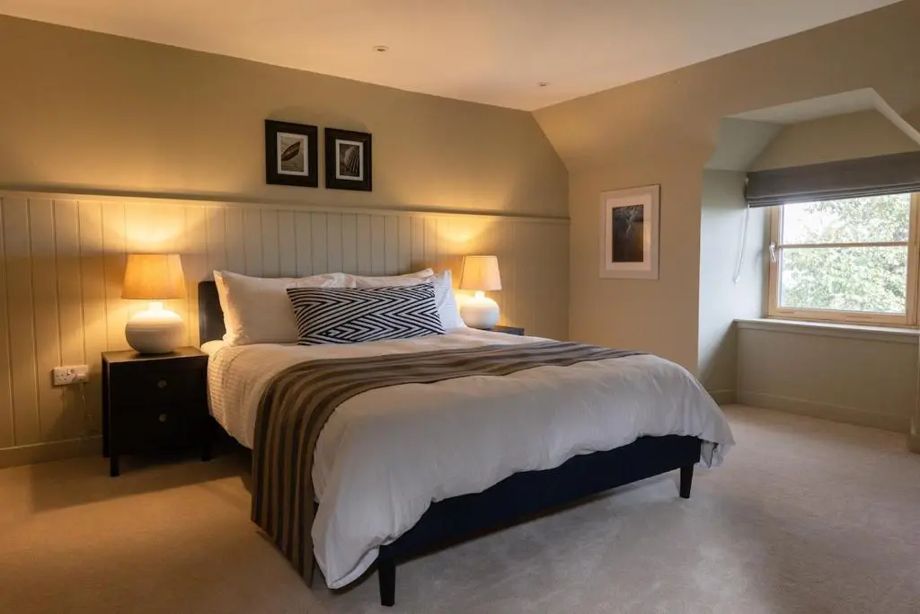 a bedroom with a bed with two lamps and a window at Luxury Farmhouse, near Dornoch