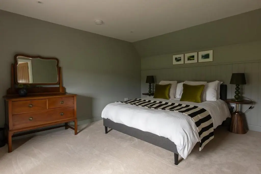 a bedroom with a bed and a dresser with a mirror at Luxury Farmhouse, near Dornoch