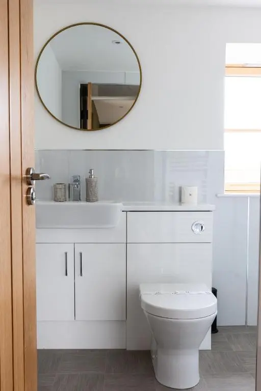 a bathroom with a white toilet and a mirror at Luxury Farmhouse, near Dornoch