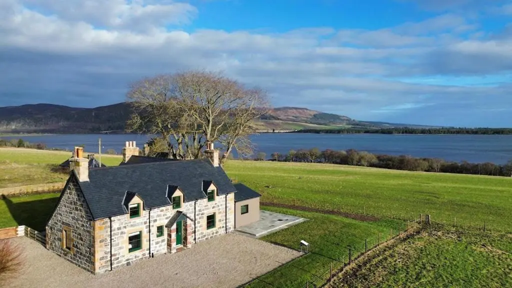 an aerial view of a house in a field next to a lake at Luxury Farmhouse, near Dornoch