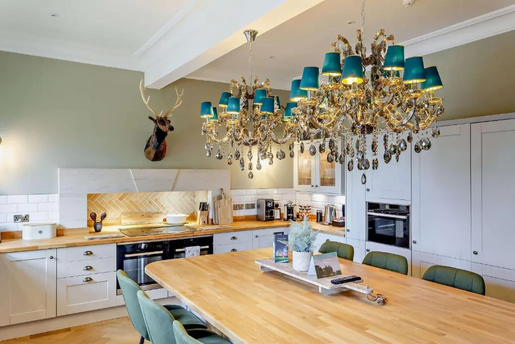 a kitchen with a wooden table and a chandelier at Muckrach Country House in Skye of Curr