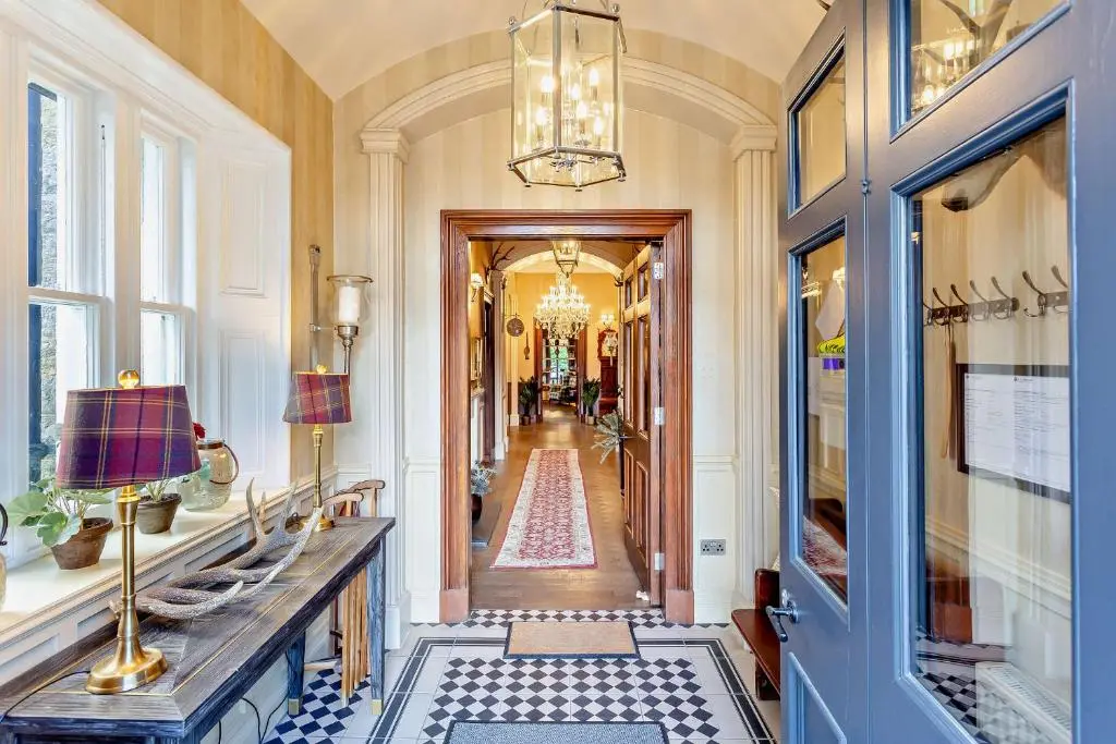 a hallway with a chandelier and a hallway with a hallwayngth at Muckrach Country House in Skye of Curr