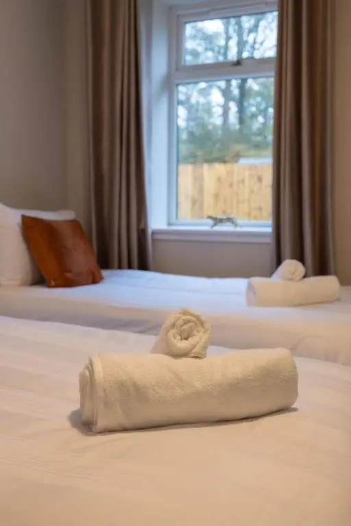 a hotel room with two beds with towels on them at Roos Cottage in Ellon