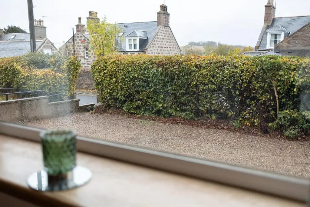 a view of a hedge from a window at Roos Cottage in Ellon