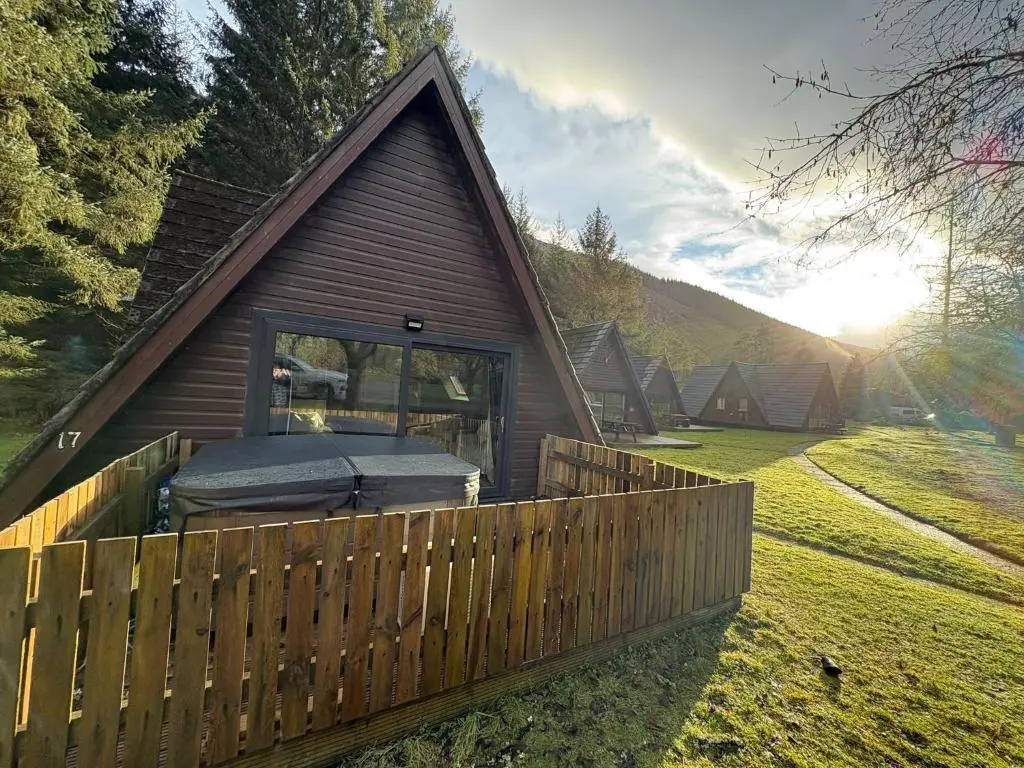 a log cabin with a fence and a porch at The Great Glen Getaway Lodge in Spean Bridge