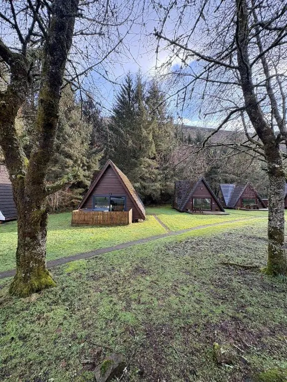 a group of cottages in a field with trees at The Great Glen Getaway Lodge in Spean Bridge