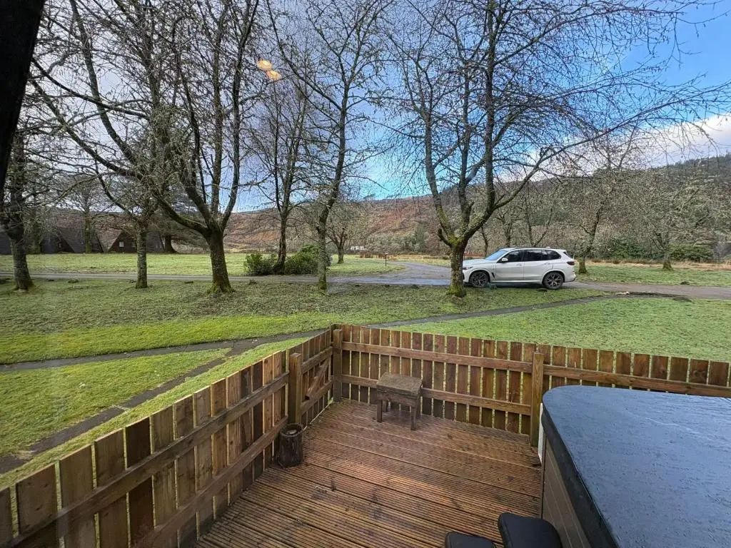 a wooden deck with a car parked in a park at The Great Glen Getaway Lodge in Spean Bridge