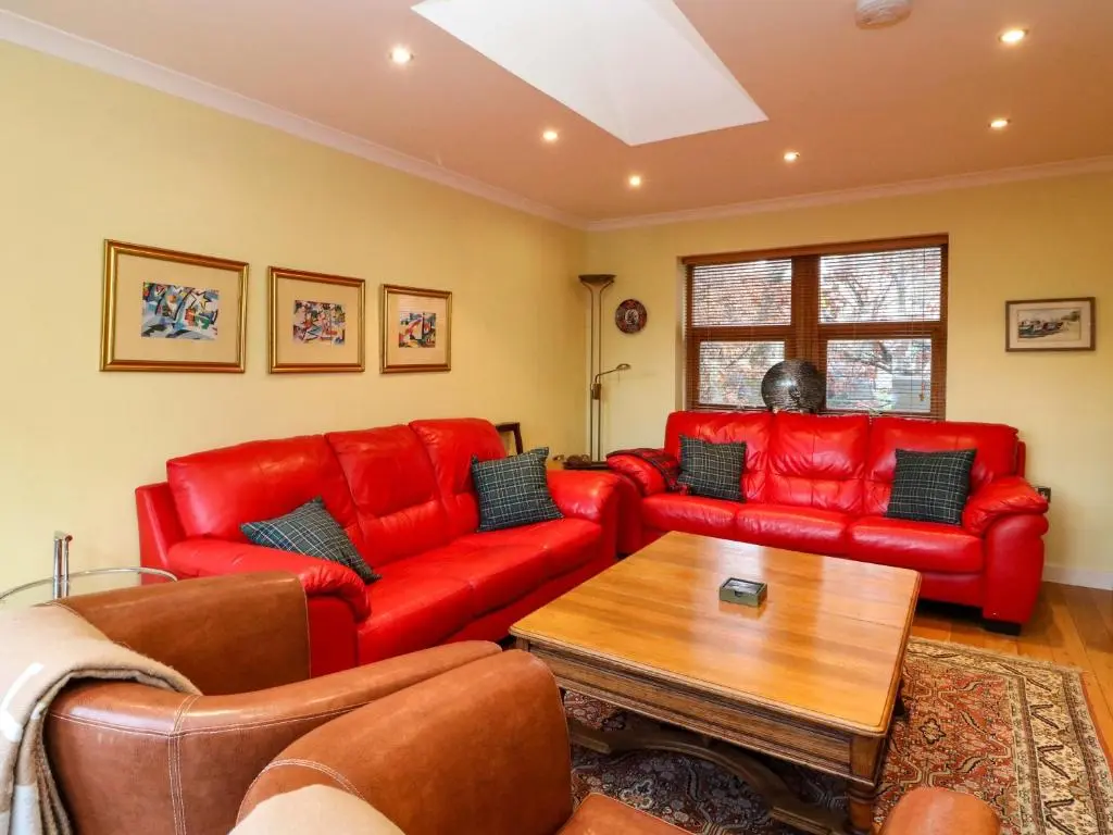 a living room with red leather couches and a table at 78 Findhorn in Forres