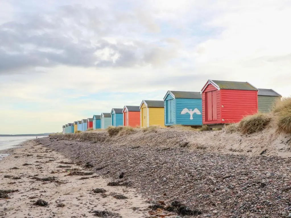 a row of colorful beach huts on a beach at 78 Findhorn in Forres