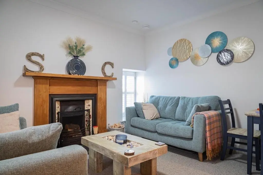a living room with a blue couch and a fireplace at Sea Crest - Beachfront Escape with Whisky Snug in Cullen