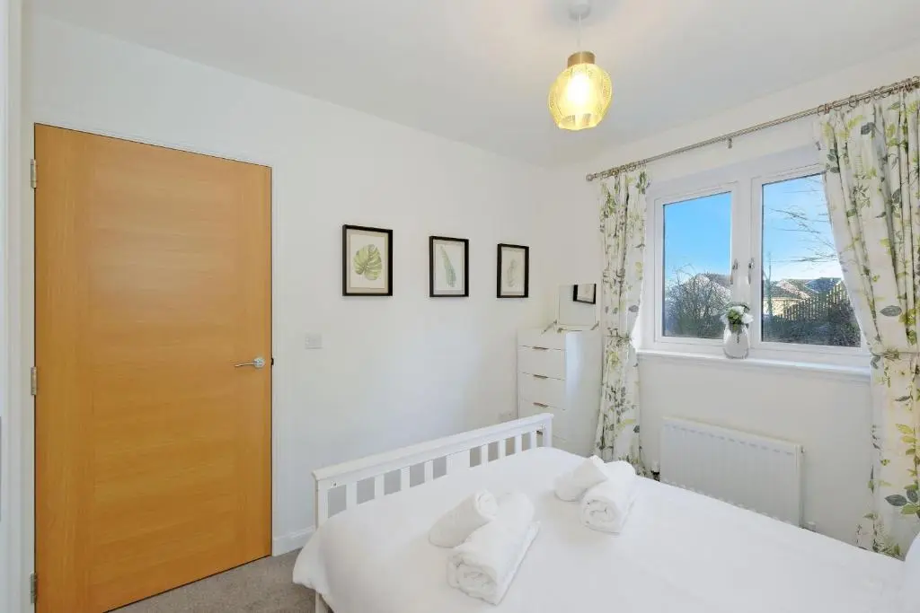 a bedroom with a white bed and a window at A comfortable and modern 2BR 2BA home near ABZ in Inverurie