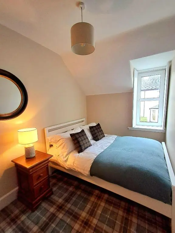 a bedroom with a bed with a lamp and a window at 42 in the Crown in Inverness