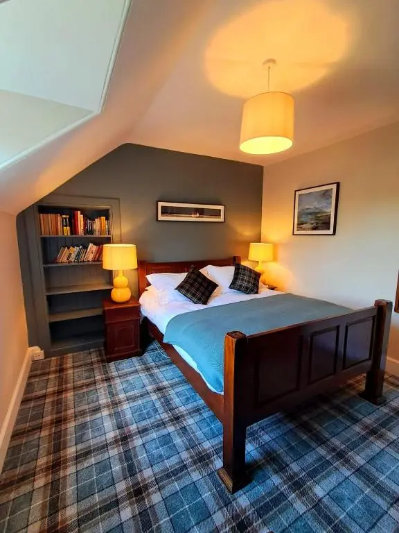 a bedroom with a bed with two lamps and a book shelf at 42 in the Crown in Inverness