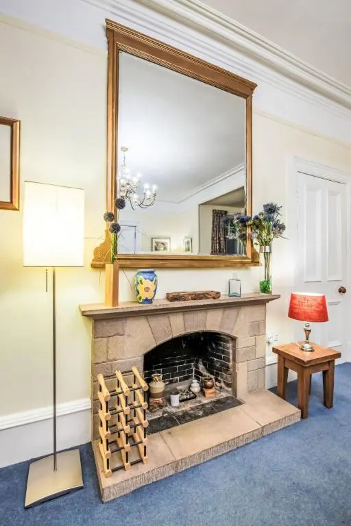 a living room with a fireplace with a large mirror at Villa Netherwood by Interhome in Newtonmore