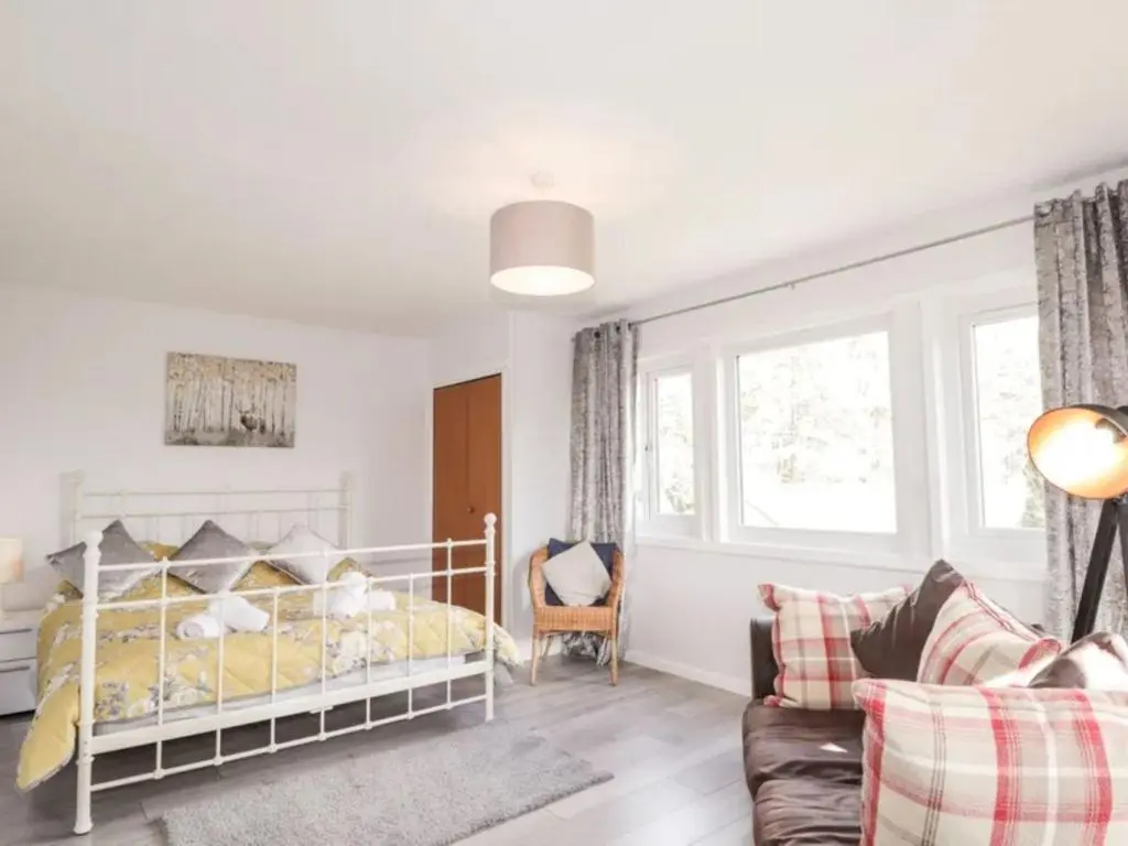a bedroom with a white bed and a couch at Holiday Home Greenaway by Interhome in Skye of Curr