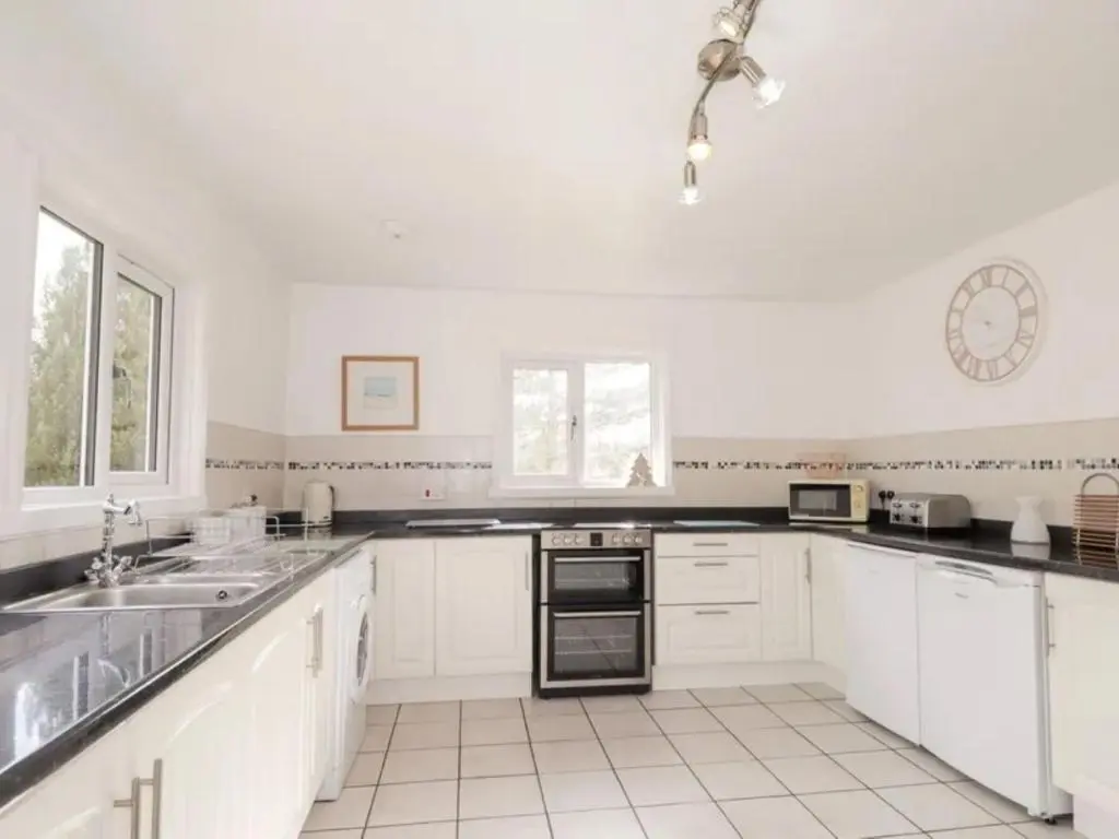 a kitchen with white cabinets and black counter tops at Holiday Home Greenaway by Interhome in Skye of Curr