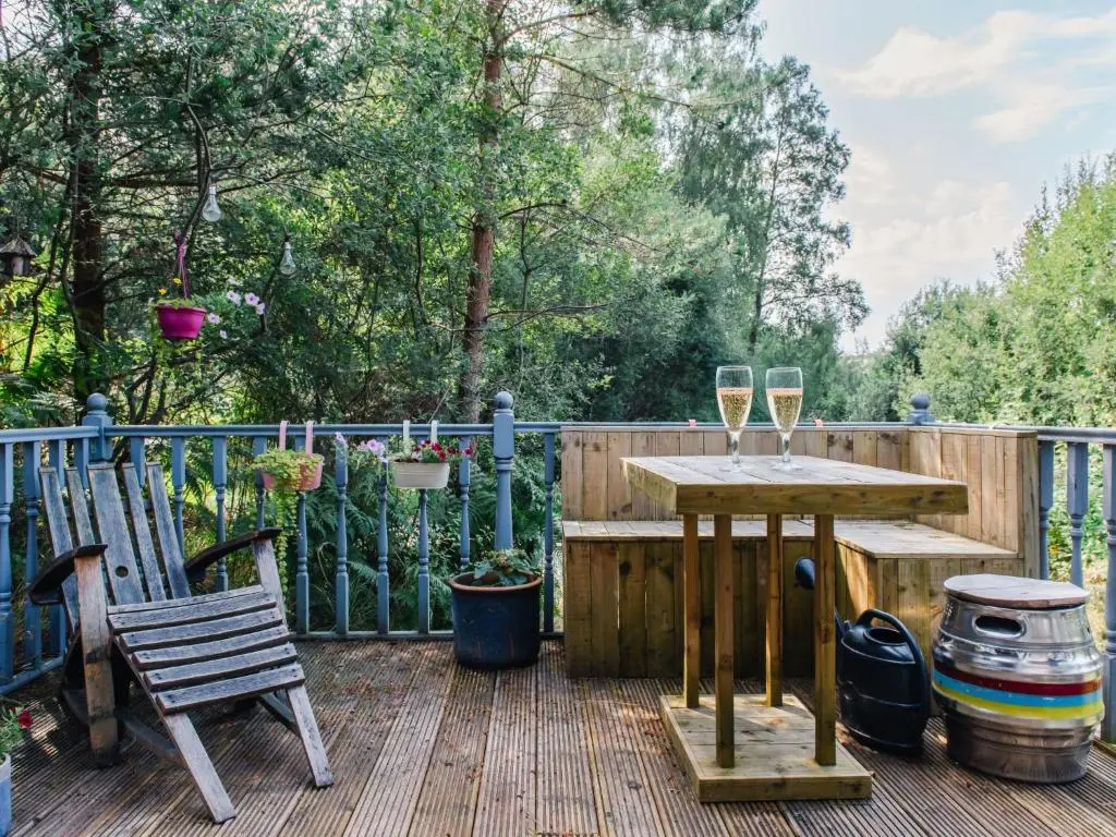 a wooden deck with a table and two glasses of wine at Chalet The Cabin by Interhome in Eskadale