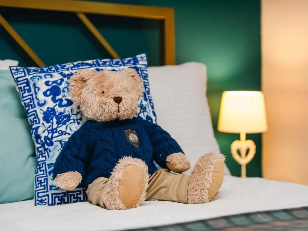 a teddy bear sitting on a bed next to a pillow at Chalet The Cabin by Interhome in Eskadale