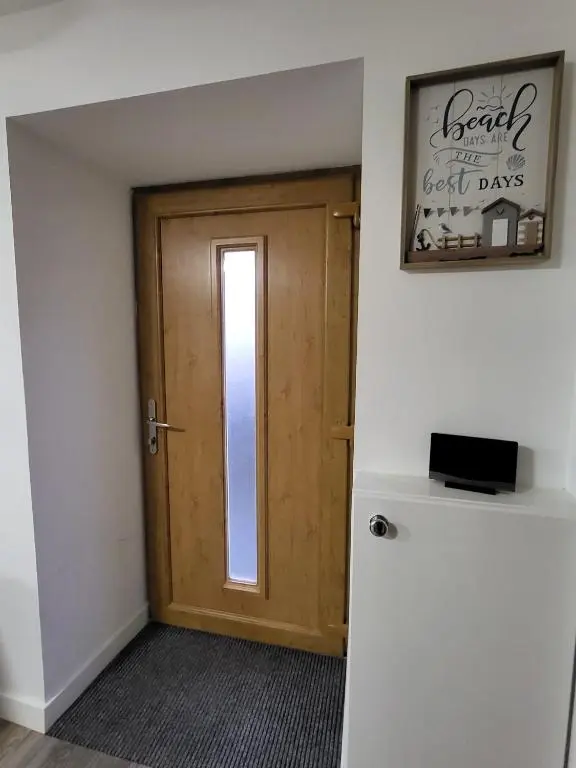 a room with a door and a sign and a refrigerator at Harbour Nights Lossiemouth in Lossiemouth