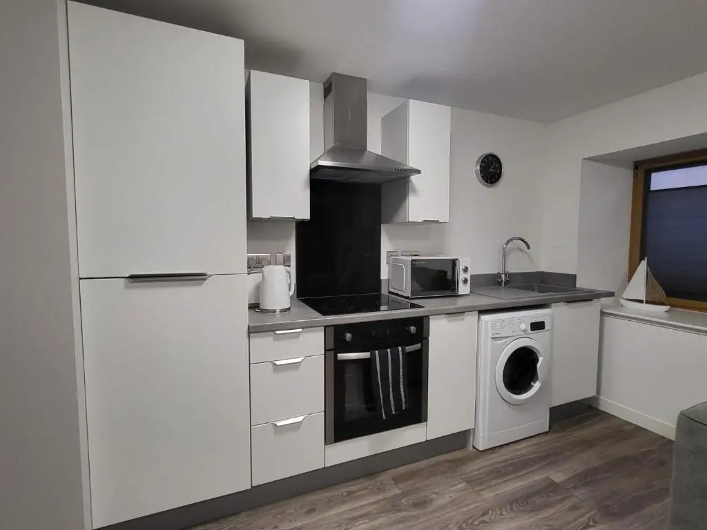 a kitchen with white cabinets and a washer and dryer at Harbour Nights Lossiemouth in Lossiemouth