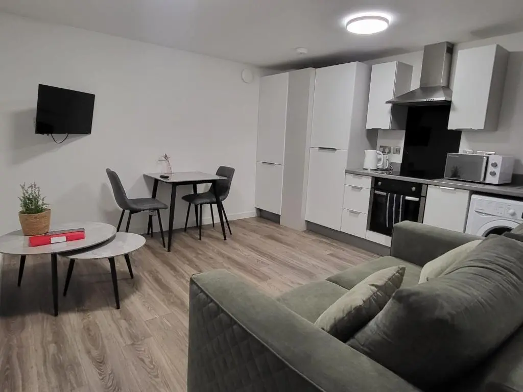 a living room with a couch and a table and a kitchen at Harbour Nights Lossiemouth in Lossiemouth