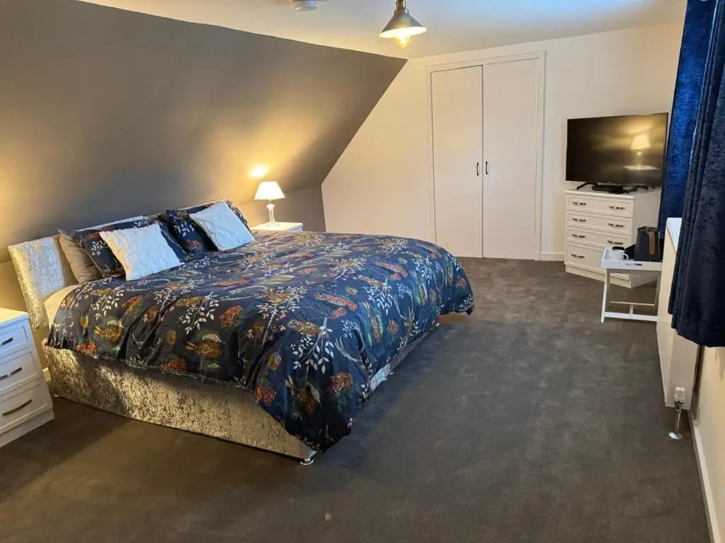a bedroom with a large bed and a television at Woodlands Banff in Banff
