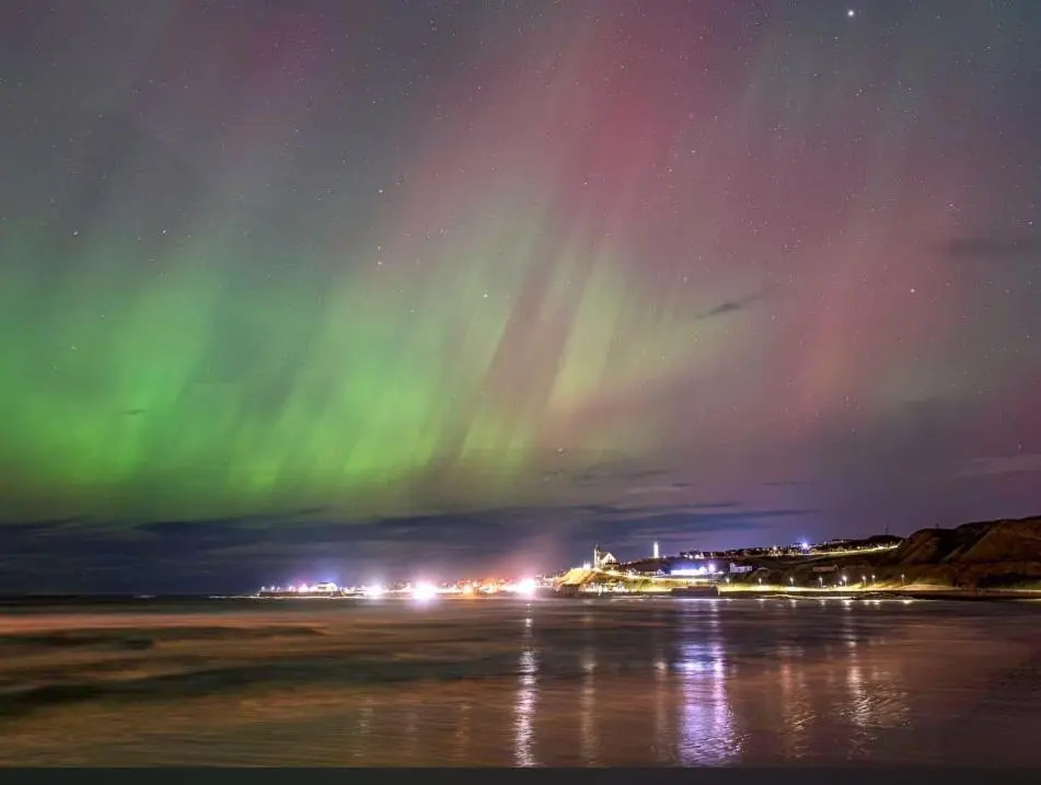 an aurora in the sky over a beach at night at Woodlands Banff in Banff