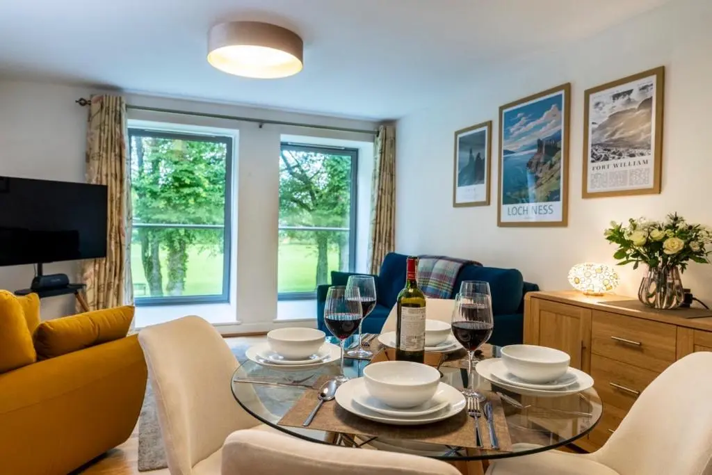 a living room with a table with wine glasses at Calder apartment Raven Wing in Fort Augustus