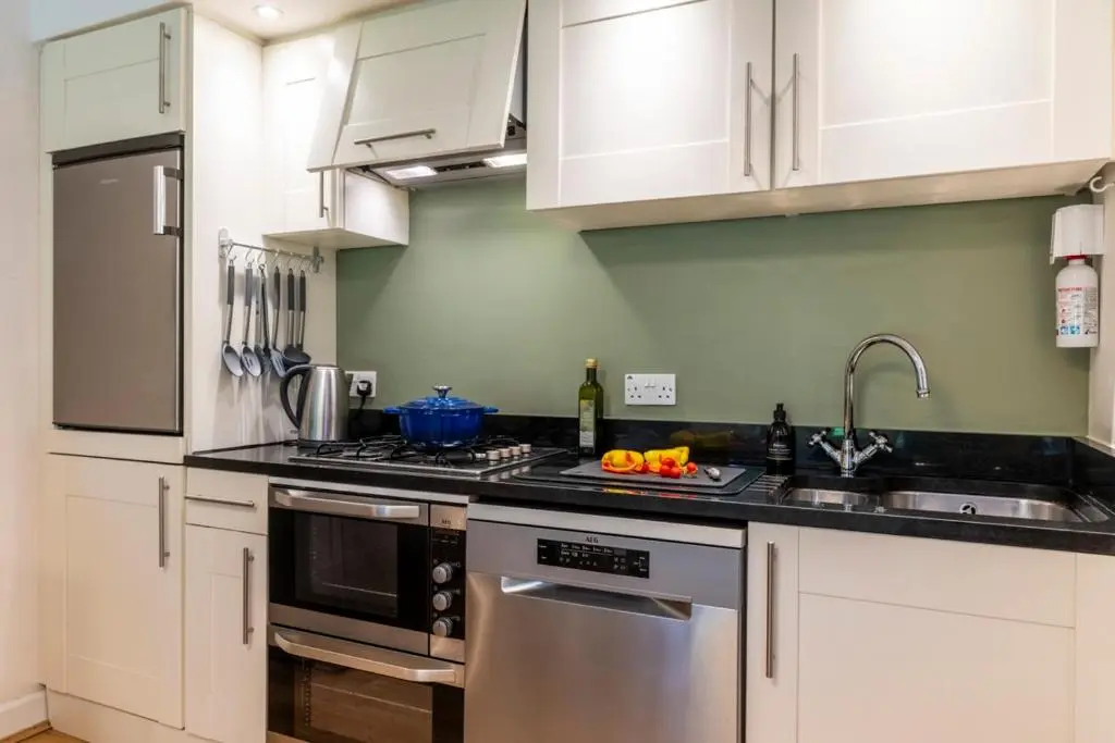 a kitchen with white cabinets and a stove top oven at Calder apartment Raven Wing in Fort Augustus