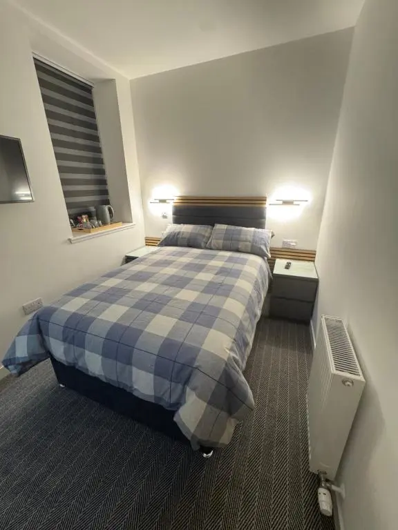 a bedroom with a bed with a blue and white plaid blanket at TSB Rooms in Turriff
