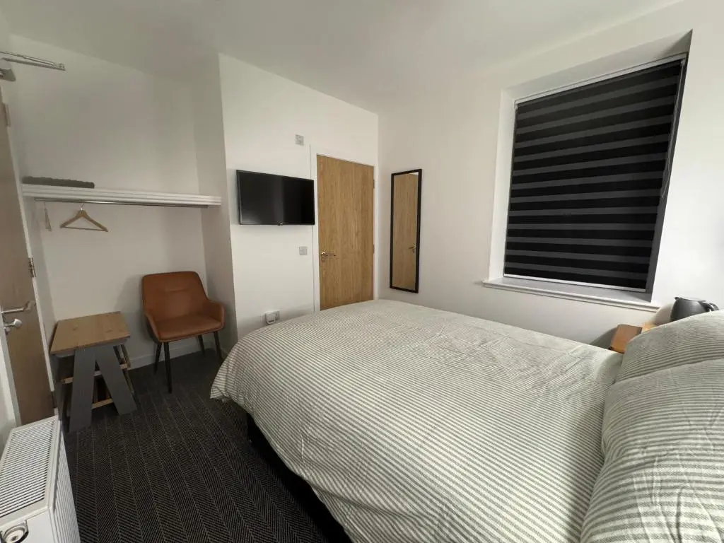 a bedroom with a bed and a desk and a window at TSB Rooms in Turriff
