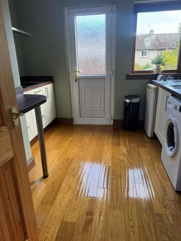 an empty kitchen with a washing machine and a wooden floor at Aberdeen Home near City in Aberdeen