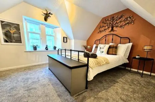 a bedroom with a bed with a tree on the wall at Inverness City Escape! in Inverness