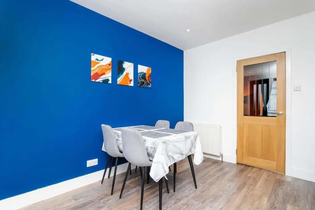 a dining room with a blue wall and a table and chairs at Airport apartment - Aberdeen - Free Parking in Aberdeen