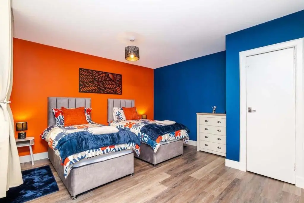 two beds in a room with orange and blue walls at Airport apartment - Aberdeen - Free Parking in Aberdeen