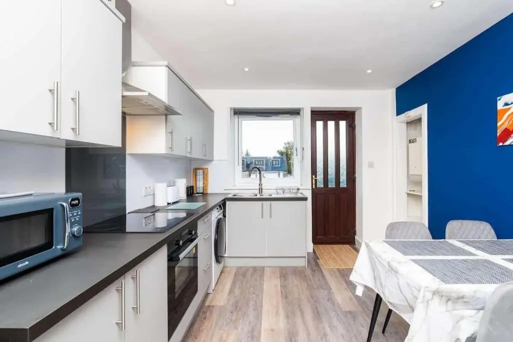 a kitchen with white cabinets and a blue wall at Airport apartment - Aberdeen - Free Parking in Aberdeen