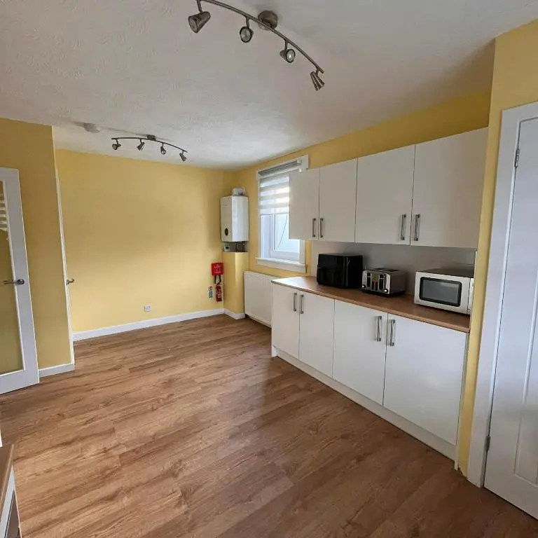 a kitchen with white cabinets and a microwave at Evan Barron Apartment, Inverness in Inverness