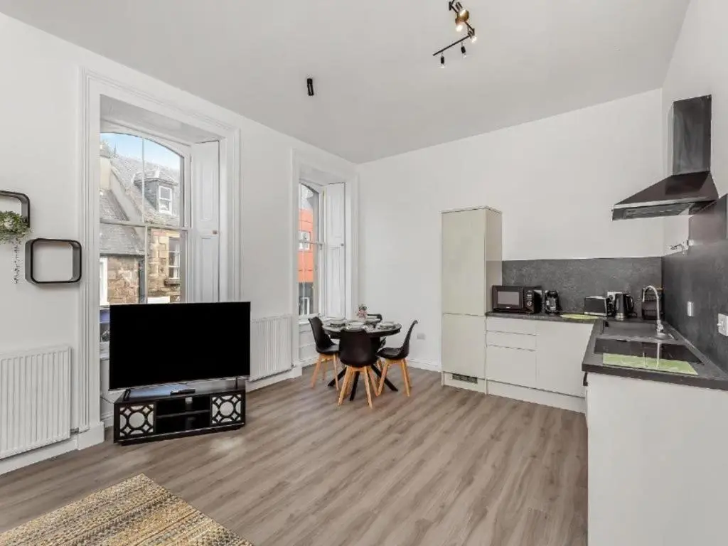 a white kitchen with a table and a tv in it at Family - Parking - Central - Wifi - Sleeps 4 in Inverness