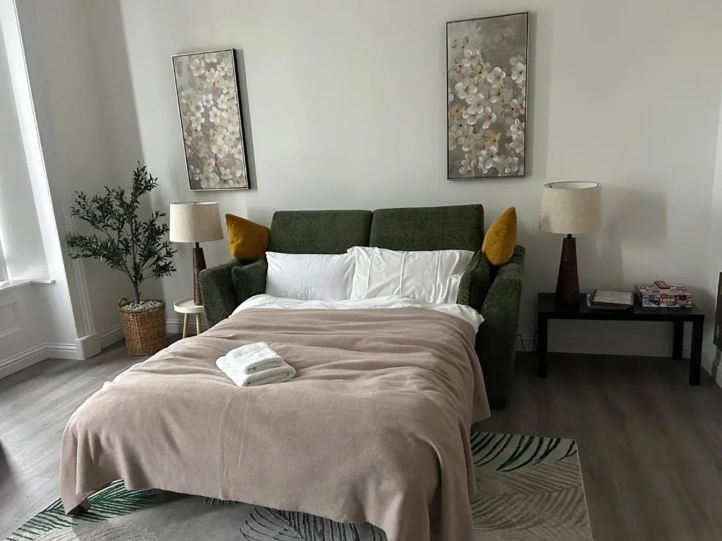 a bedroom with a large bed and a green couch at Family - Central - Parking - Wifi - Sleeps 4 in Inverness